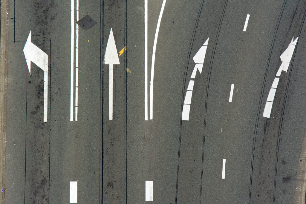 High-angle view of asphalt road with directional arrows and lane markings.